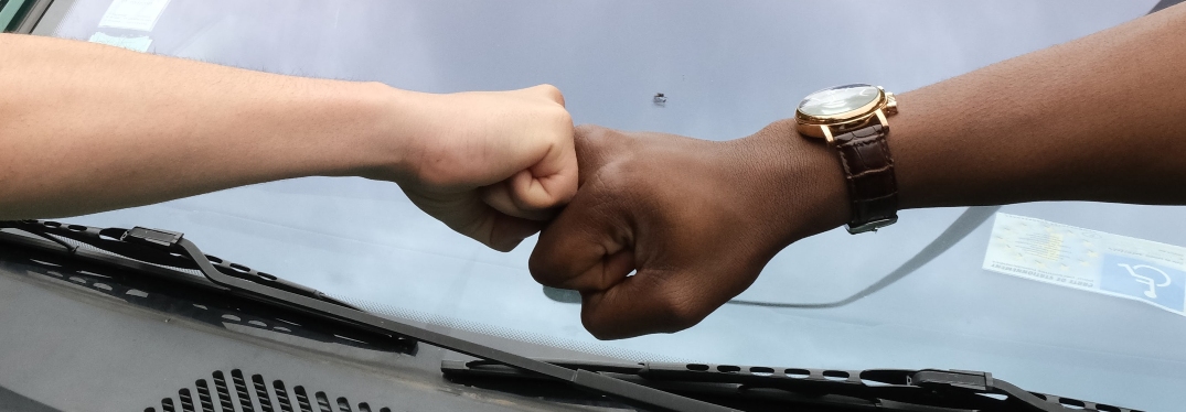 two people fist bumping over car